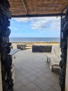 a patio with a bench and a view of the beach at Dammuso Sul mare MDQ Sea in Pantelleria