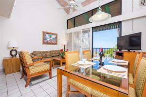 Maui Schooner Resort في كيهي: غرفة معيشة مع طاولة وكراسي وتلفزيون
