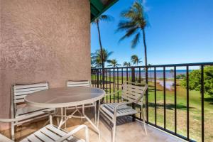 Maui Schooner Resort في كيهي: طاولة وكراسي على شرفة مطلة على المحيط
