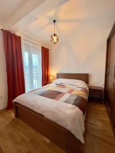 a bedroom with a bed and a window with red curtains at Mima Apartment in Kolašin
