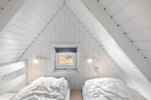 two beds in a white room with a window at First Camp Frigård Camping & Cottages in Kruså