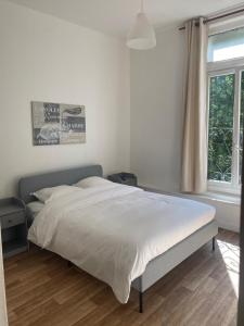 ein Schlafzimmer mit einem großen Bett mit weißer Bettwäsche und einem Fenster in der Unterkunft HOTEL DU CENTRE in Roubaix