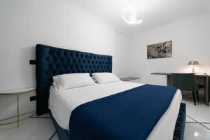 una camera con un grande letto con testiera blu di Apartments Hotel Real Suite Napoli Chiaia Mergellina a Napoli