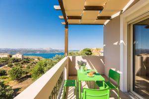 een balkon met een groene tafel en stoelen en de oceaan bij Villa Alysso in Megála Khoráfia