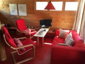 salon z 2 czerwonymi krzesłami i stołem w obiekcie Haus Pfahl w mieście Bellwald