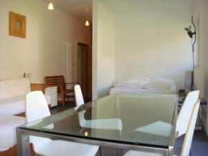 een glazen tafel met witte stoelen en een kamer met een bed bij La Montanella 7 in Maloja
