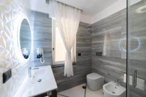 a bathroom with a sink and a toilet and a mirror at Apartments Hotel Real Suite Napoli Chiaia Mergellina in Naples