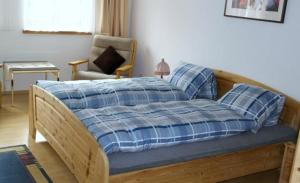 a bed with a blue plaid blanket and a chair at Ers Curtins in Zernez