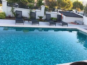 a swimming pool with chairs next to a building at merkezde 8 kişilik özel havuzlu villa in Fethiye