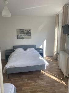ein weißes Schlafzimmer mit einem Bett und Holzboden in der Unterkunft HOTEL DU CENTRE in Roubaix