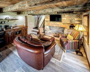 a living room with a leather couch and a stone fireplace at 1786 Farm Cottage Honeymoon Suite Renovated 2022 in Chester