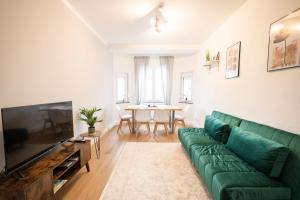 a living room with a green couch and a table at DWELLSTAY - Wohnung 90qm, 3 Schlafzimmer, Küche, Wohnzimmer, Balkon, Netflix in Fulda