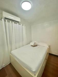 a small white room with a bed with white curtains at Tiny Room Hura Homes II Condominium Unit Visayas Avenue QC in Manila