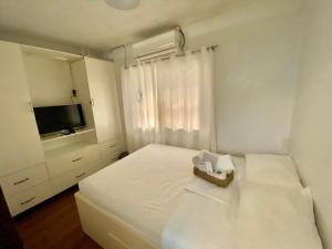 a white bedroom with a bed and a television at Tiny Room Hura Homes II Condominium Unit Visayas Avenue QC in Manila