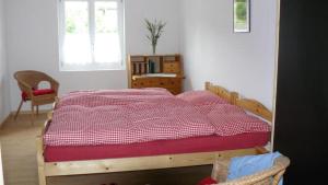 a bedroom with a bed with a red and white comforter at Sunneggli in Aeschi bei Spiez