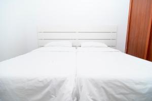 a white bed with white sheets and pillows at Alojamientos el Bajón in La Restinga