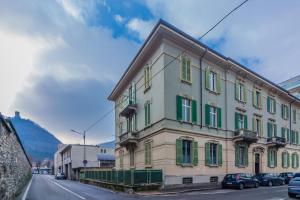 un edificio con ventanas de contraventanas verdes en una calle en Casa Magenta en Como