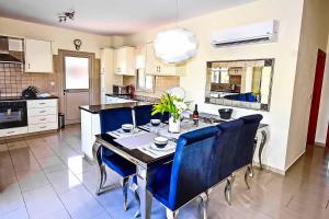 a kitchen with a table with blue chairs in it at Villa Golden Coral in Peyia