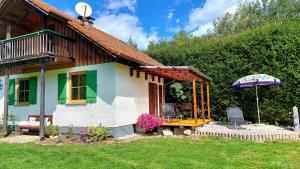 a small house with a table and an umbrella at Ferienhaus auf dem Werteshof in Peißenberg