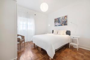 1 dormitorio blanco con 1 cama y 1 silla en Coral Apartment by Olala Homes, en Cascais
