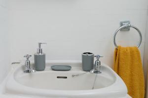 un lavandino bianco con due rubinetti e un asciugamano giallo di Spacious 3 Bedroom Apartment- Crouch End a Londra