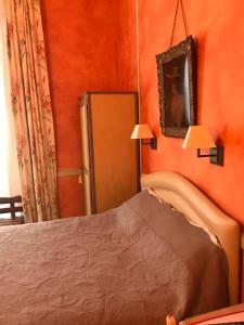 a bedroom with orange walls and a bed and a mirror at Hotel de la Sologne in Beaugency