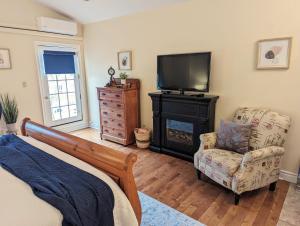 1 dormitorio con 1 cama, TV y silla en Suites On King, en Niagara on the Lake