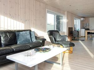 a living room with a black leather couch and a white table at Two-Bedroom Holiday home in Børkop 9 in Egeskov