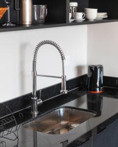 a stainless steel sink in a black kitchen at Mirante do Serjoca no Centro Histórico in São Paulo