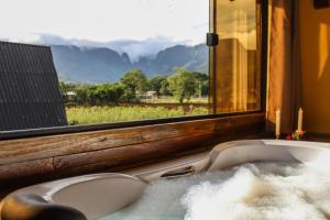 a bath tub in front of a window with a view at Pousada Rancho Alvorada in Praia Grande