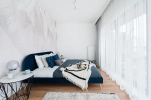 sypialnia z niebieskim łóżkiem i białą ścianą w obiekcie Lake Club Apartments - LoftAffair w mieście Mikołajki