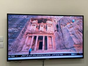 einen Fernsehbildschirm mit einem Bild eines Gebäudes in der Unterkunft Treasury Terrace Apartments in Wadi Musa