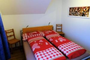 a bed with two red and white pillows on it at Ferienwohnung Rätia mit Bodenseeblick in Wolfhalden 