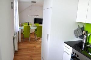 a kitchen with a white refrigerator and a table with green chairs at Ferienwohnung Rätia mit Bodenseeblick in Wolfhalden 
