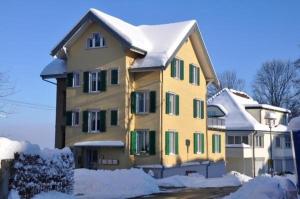 een geel huis met sneeuw erop bij Ferienwohnung Rätia mit Bodenseeblick in Wolfhalden 