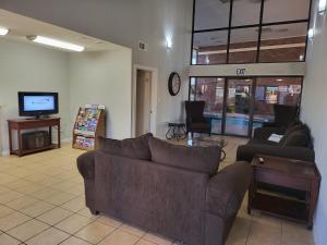 ein Wohnzimmer mit Sofas und einem Flachbild-TV in der Unterkunft Blue Ribbon Inn and Suites in Sallisaw