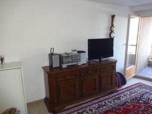 ein Wohnzimmer mit einem TV auf einem Holzschrank in der Unterkunft Wohnung mit herrlichem Blick auf den Pilatus in Weggis