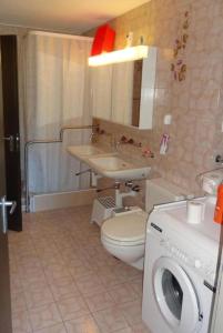 a bathroom with a toilet and a sink and a washing machine at Wohnung mit herrlichem Blick auf den Pilatus in Weggis