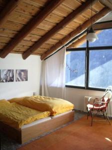 ein Schlafzimmer mit einem Bett, einem Stuhl und einem Fenster in der Unterkunft Casa Cresmino in Cavigliano