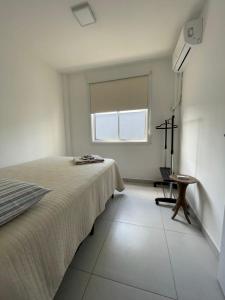Habitación blanca con cama y ventana en Meu cantinho em Floripa!, en Florianópolis