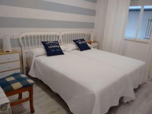 1 Schlafzimmer mit 2 weißen Betten und blauen Kissen in der Unterkunft Piso 4-5 pax (001) 140m de playa Caneliñas, P. Baja in Sanxenxo