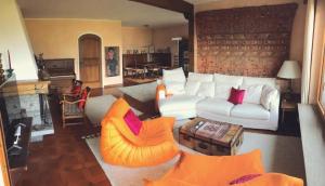ein Wohnzimmer mit einer weißen Couch und einem orangenen Stuhl in der Unterkunft Casa Nespole, Familiennest mit Seesicht in Minusio