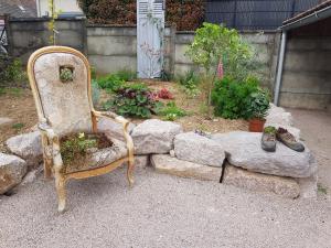 une vieille chaise assise dans un jardin avec des rochers dans l'établissement Gite le K'lin d'Oeil, à Epfig