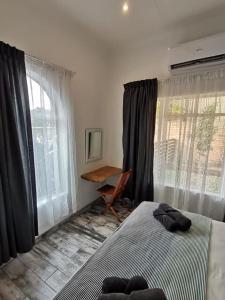 a bedroom with a bed and a desk and windows at 34 Hornbill Street in St Lucia