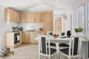 a kitchen with wooden cabinets and a white table and chairs at First Camp Klim Strand - Nordvestkysten in Fjerritslev