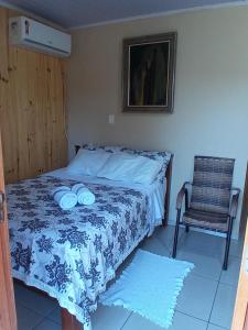 a bed in a room with a chair and a bed with blue and white sheets at Hotel cabanas bom Jesus in Ametista do Sul