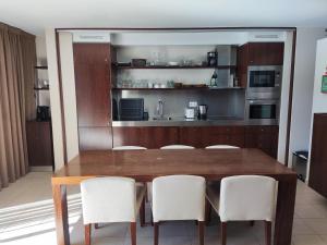 uma cozinha com uma mesa de madeira e cadeiras brancas em Salgados Beach&Golf - Praia dos Salgados em Albufeira