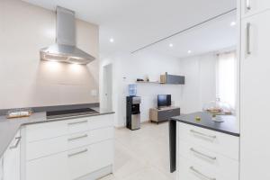 a kitchen with white cabinets and a black counter top at Playa - PLAZA AYUNTAMIENTO ALICANTE in Alicante