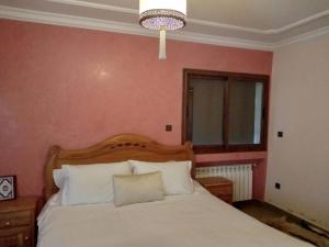 a bedroom with a white bed with a pink wall at حاتم للعقارات افران المغرب in Ifrane