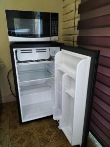 Elle comprend un réfrigérateur blanc avec une porte ouverte et un four micro-ondes. dans l'établissement LOFT PLAYAS "A" , a unos pasos del malecon estadio acuario y letras, à Mazatlán